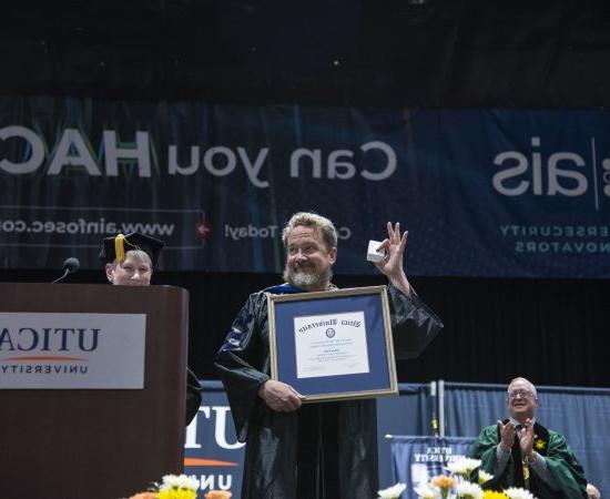 Dr. 亚当包 holds up the framed Crisafulli Award at the 2024 Commencement Ceremony.